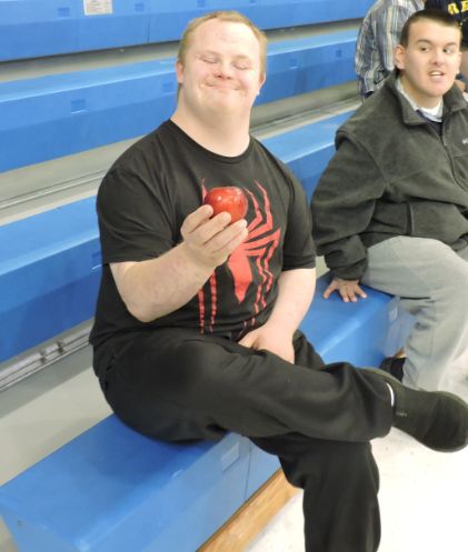 A student smiles with a red apple.